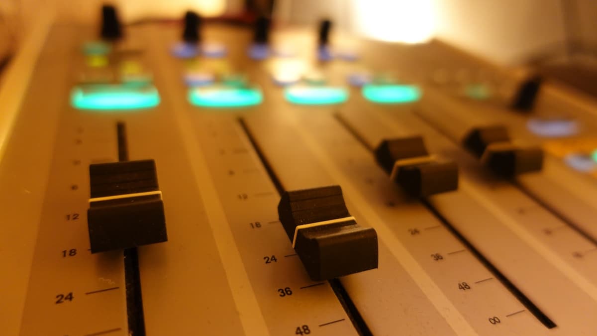 Close-up of professional audio mixing desk with illuminated faders